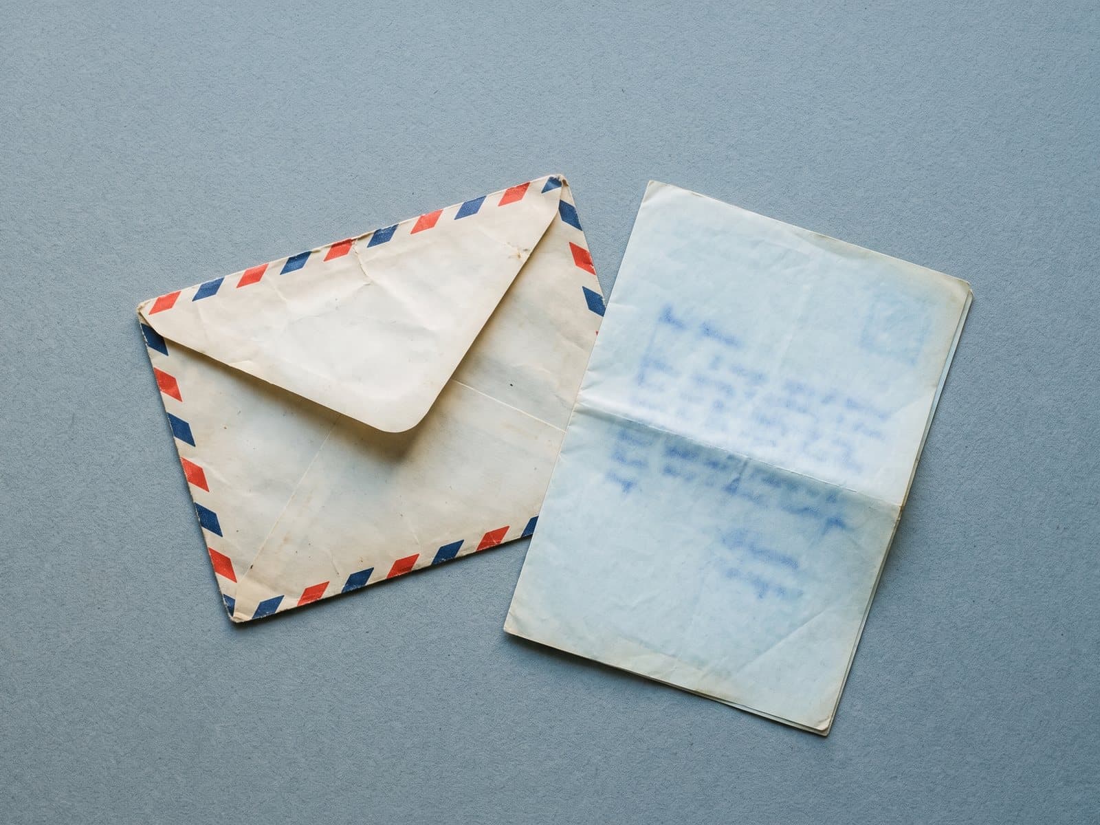 An airmail envelope with a folded blue letter half drawn out of it.